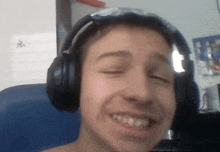a young man wearing headphones and sunglasses is smiling and looking at the camera .