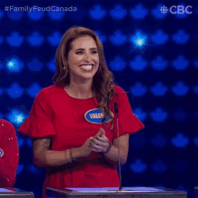 a woman in a red dress is standing in front of a microphone on a tv show .