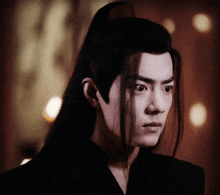 a man with long black hair is looking at the camera