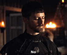 a man with a beard says no in a dark room with candles