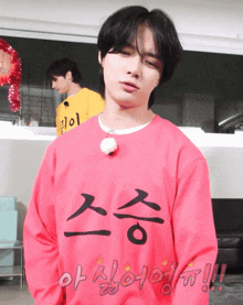 a young man wearing a pink sweater with chinese writing on it