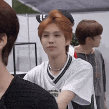 a man with red hair is wearing a white shirt that says ' abercrombie ' on it