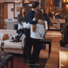 a man is hugging a woman in a living room with other people .