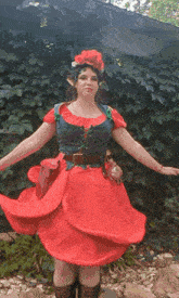 a woman in a red dress with a flower in her hair is standing with her arms outstretched