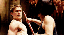 a man and a woman are fighting with sticks