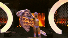 a woman in a purple outfit is dancing on a stage with a sign that says aew