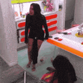 a woman in a black dress is standing in front of a vanity