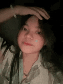 a young woman is holding her hand to her forehead and smiling .