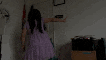 a woman in a purple dress is standing in front of a door in a room .