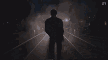 a person is running on a train track at night with a s on the bottom left