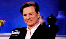 a man in a suit is smiling in front of a blue background that says katie