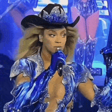 a woman is wearing a cowboy hat and holding a microphone