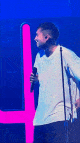 a man in a white shirt is singing into a microphone on stage