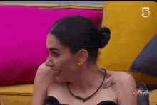 a woman is sitting on a couch wearing a black top and a bun .