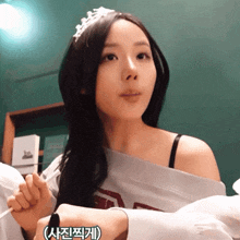 a woman wearing a tiara and a shirt with the letter t on the shoulder