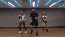 a man is dancing with two women in a dance studio .