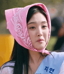 a woman wearing a pink bandana on her head and a sash with korean writing on it