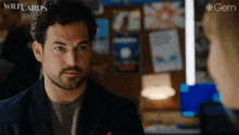 a man with a beard is looking at a woman with wildcards written on the bottom of the screen