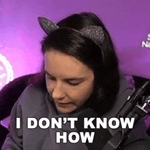 a woman wearing cat ears is sitting in front of a microphone and saying `` i don 't know how ''