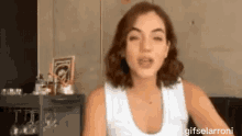 a woman in a white tank top is sitting on a couch and talking