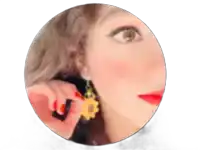 a woman wearing a pair of sunflower earrings looks at the camera