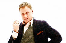a man wearing a plaid jacket and vest is giving a middle finger