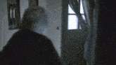 a man in a suit and tie is opening a door in a dark room