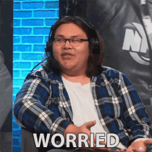 a man wearing headphones and a plaid shirt is sitting in front of a sign that says worried