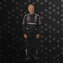 a man in a petronas suit stands in front of a dark background