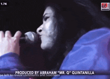 a woman in a blue jacket is on a screen that says 1.7k