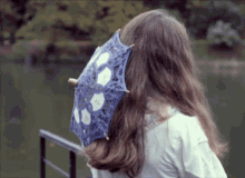 a woman is holding a blue umbrella over her head