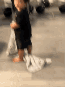 a blurry picture of a person standing on a concrete floor with a blanket on the floor .