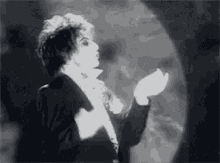 a black and white photo of a woman in a tuxedo dancing in a dark room .