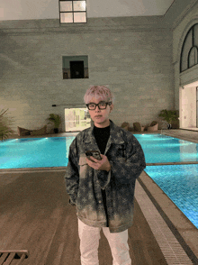 a man standing in front of a large swimming pool holding a cell phone