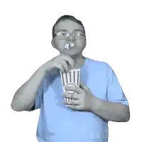 a man in a blue shirt is eating popcorn from a striped container