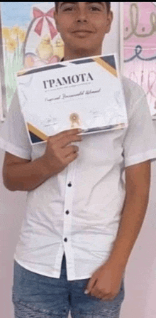 a young man in a white shirt is holding a certificate over his face .