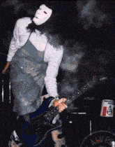 a man wearing a white mask is playing a guitar
