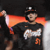 a baseball player wearing a black jersey with giants on it