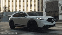 a white acura car is driving down a street