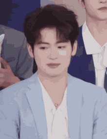a man in a blue suit and white shirt is looking at the camera