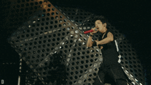 a man singing into a red microphone with the letter d in the lower right corner