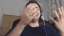 a man wearing headphones is making a funny face while looking at his phone .