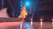 a woman in a yellow dress is dancing with a man