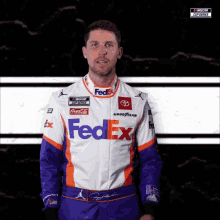 a man in a fedex racing suit stands in front of a black and white background