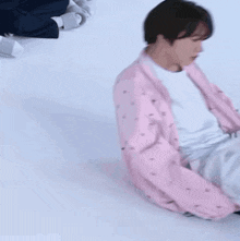 a person wearing a pink jacket is laying on the floor with their eyes closed