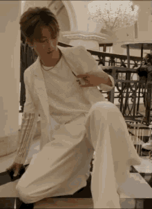 a young man in a white suit is kneeling down on the floor