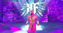 a wrestler in a pink outfit is standing in front of a purple background .