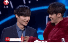 two men are standing next to each other and one of them is wearing a red fur coat with the word supreme on it