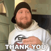 a man with a beard wearing a hat and a white sweatshirt says thank you