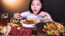 a woman is sitting at a table eating a variety of food with chopsticks